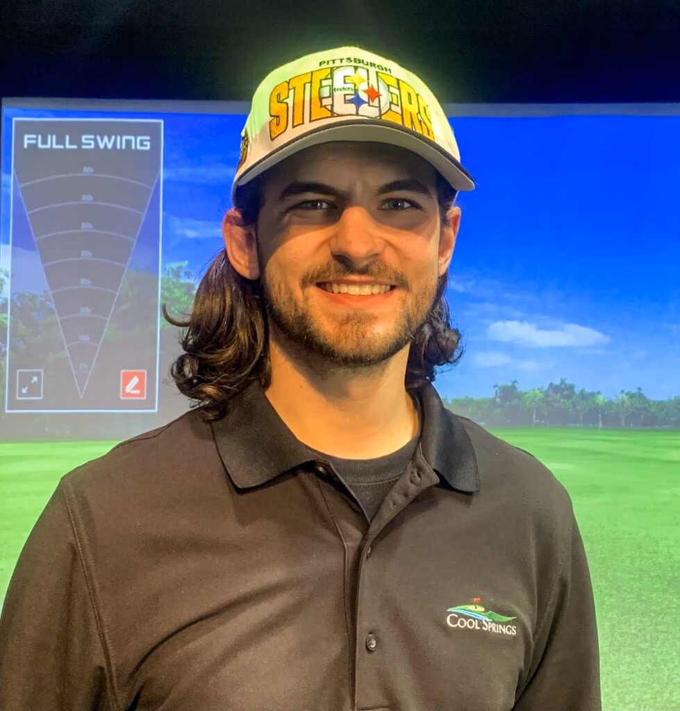 Smiling man wearing a neon green Pittsburgh Steelers hat and black polo with a Cool Springs logo, standing in front of a golf simulator backdrop showing 'FULL SWING'.